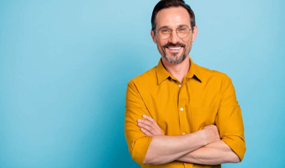 Portrait of charming mature man true boss feel content emotions wear yellow shirt isolated over blue color background