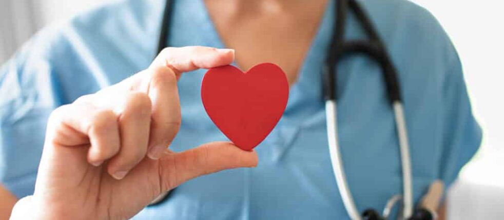 Nurse medical worker holding up red heart. Healthcare and medica